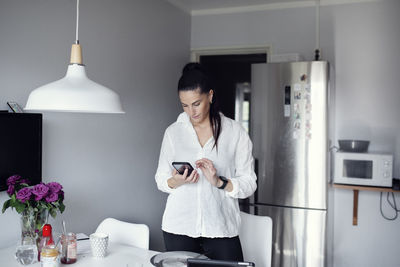 Woman in kitchen using cell phone