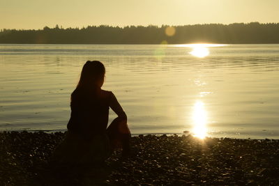 Woman standing on beach against sky during sunset