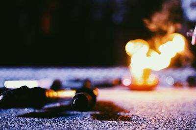 Close-up of lit candles on road at night