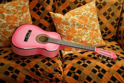 High angle view of acoustic guitar on sofa at home