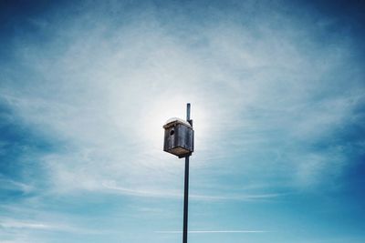 Low angle view of birdhouse on pole against blue sky