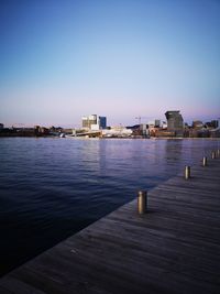 Buildings by sea against clear sky at dusk