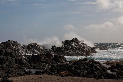 Scenic view of rocks on beach against sky