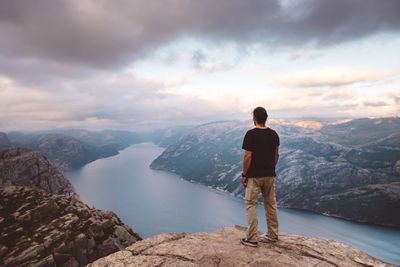 Rear view of man standing on rocks against mountains