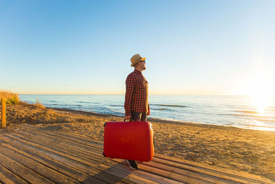 Man wearing hat on beach against clear sky