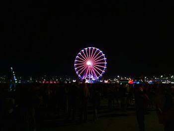 Crowd at illuminated amusement park against sky at night