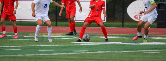 Horizontal view of a high school boys soccer game on a green turf field.