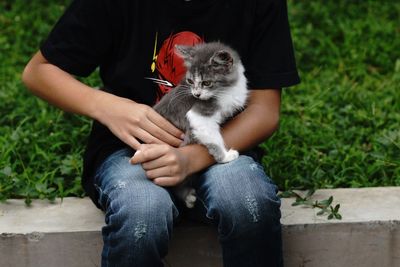 Midsection of woman with cat sitting outdoors