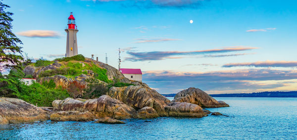 Lighthouse by sea against sky