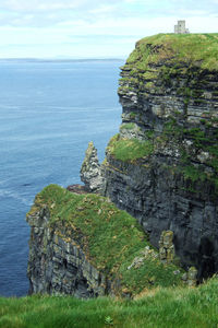 Scenic view of cliff by sea against sky