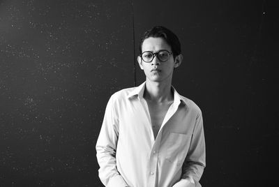 Portrait of young man standing against wall