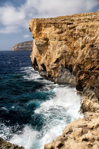 Scenic view of rocks in sea against sky