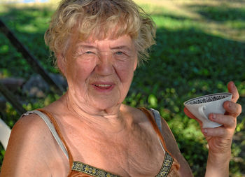 Portrait of senior woman holding coffee cup at yard