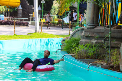 Man sitting on inflatable ring in swimming pool at water park