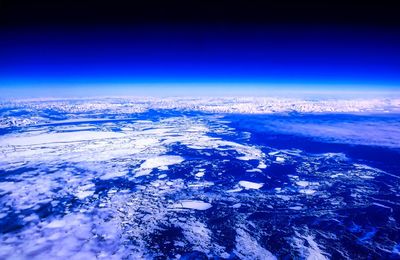 Aerial view of snowcapped landscape against blue sky