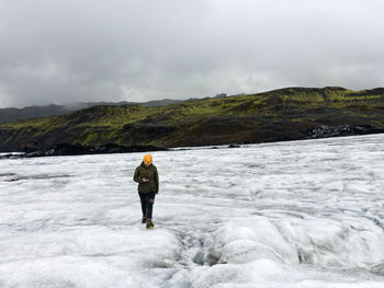 Rear view of man standing on snow covered mountain