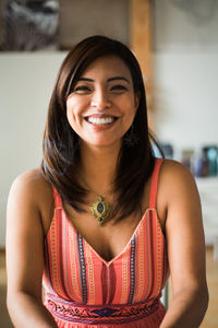 Portrait vertical image of a latina woman smiling indoors.