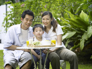 Portrait of parents and son having breakfast at backyard