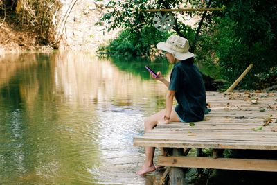 Man sitting on bench by lake