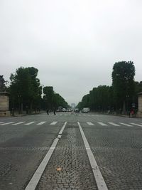 Road by trees against sky