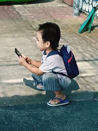 Full length of boy holding mobile phone