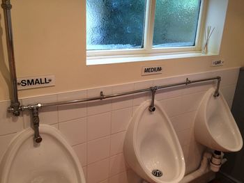 Close-up of urinals on tiled wall