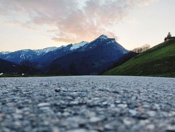 Surface level of road against mountains during sunset