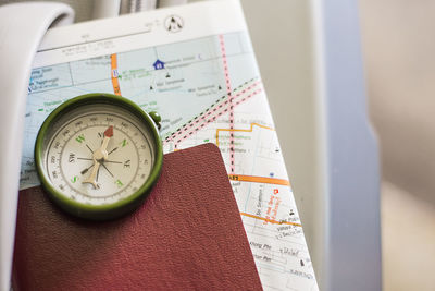 High angle view of navigational compass and passport on luggage