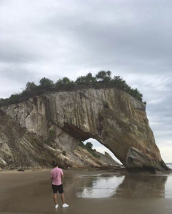 Rear view of woman standing on rock against sky