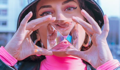 Close-up portrait of young woman holding crystal while standing in city