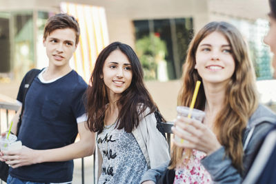 Happy teenagers looking at friend outdoors