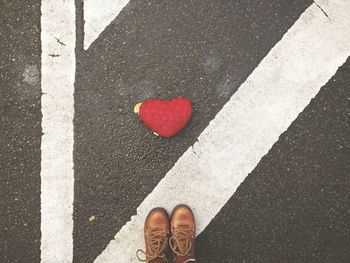 Low section of man standing by heart shape on road