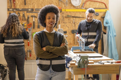 Portrait of confident female technician standing with arms crossed at recycling center