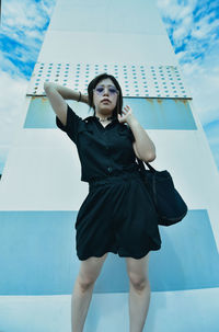 Young woman standing against wall