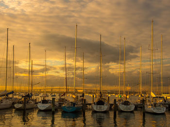 Boats moored in calm sea at sunset