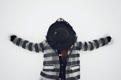 Woman in warm clothing standing against wall