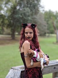 Young woman carrying dog while looking away in park