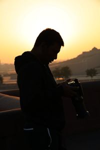 Side view of silhouette man drinking glass against sunset sky