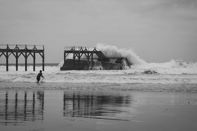 Man on pier over sea against sky