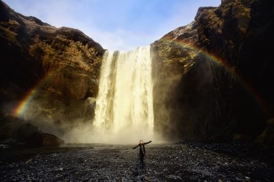 Woman standing against skogafoss waterfall