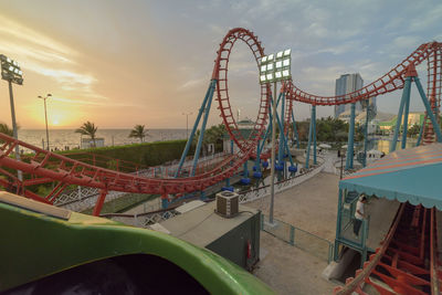 Ferris wheel at amusement park against sky during sunset