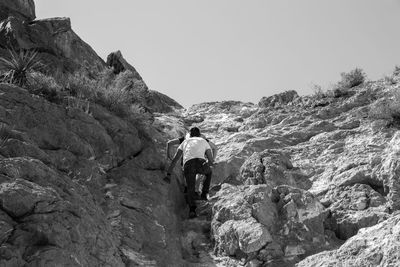 Rear view of man standing on rock against sky