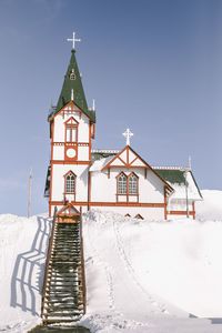 Traditional windmill on snow covered building against sky