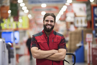 Portrait of happy salesman standing arms crossed at hardware store