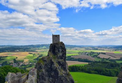 Castle on landscape against cloudy sky