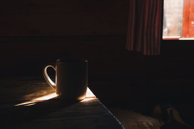 Close-up of cup on wooden table in darkroom