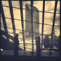 Silhouette buildings in front of glass window during sunset