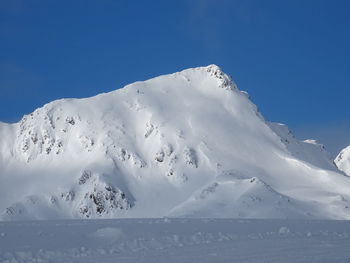 Low angle view of snowcapped mountain against blue sky