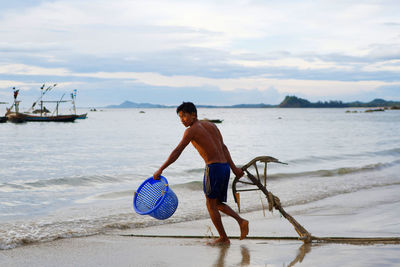 Full length of shirtless man on beach