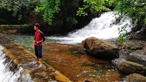 Full length of woman standing on rock in forest